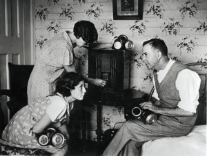 World War Two. England. 1938. The family at home, tuning in to hear the news on the radio news. They have gas masks at the ready.